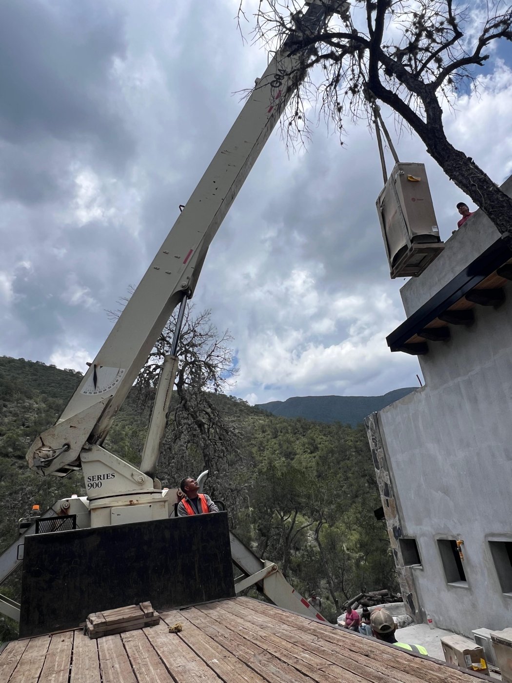 Brazo articulado instalando equipo de aire acondicionado en zona montañosa